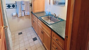 Una cucina compatta con mobili in legno, un lavello e uno specchio sopra.