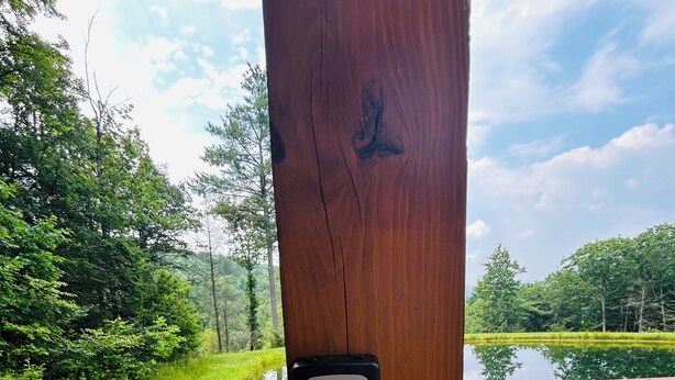 Un palo di legno con un dispositivo di sicurezza e un sentiero in pietra che conduce a un corso d'acqua.