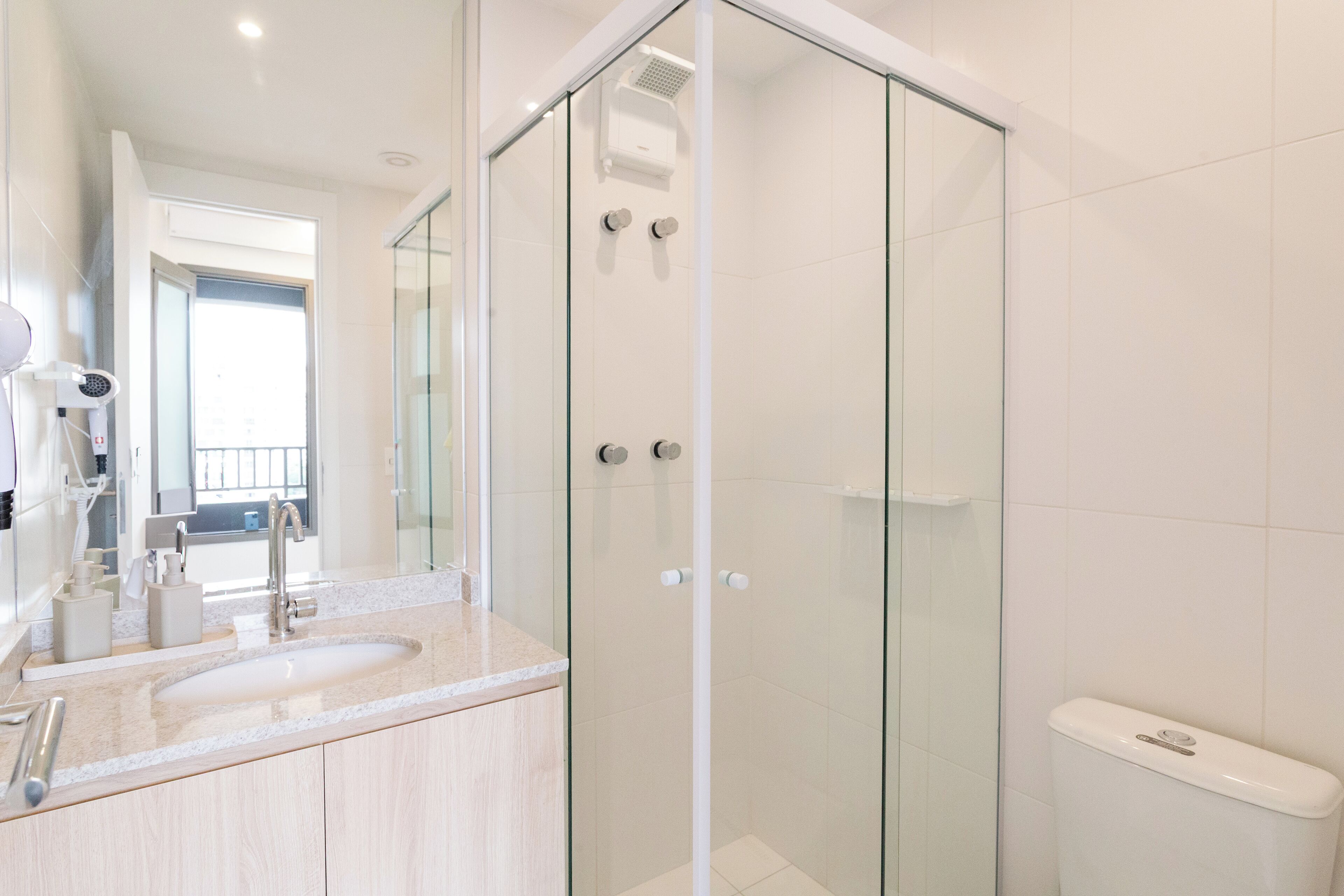 A modern bathroom with a glass-enclosed shower, a sink with a mirror, and a toilet.