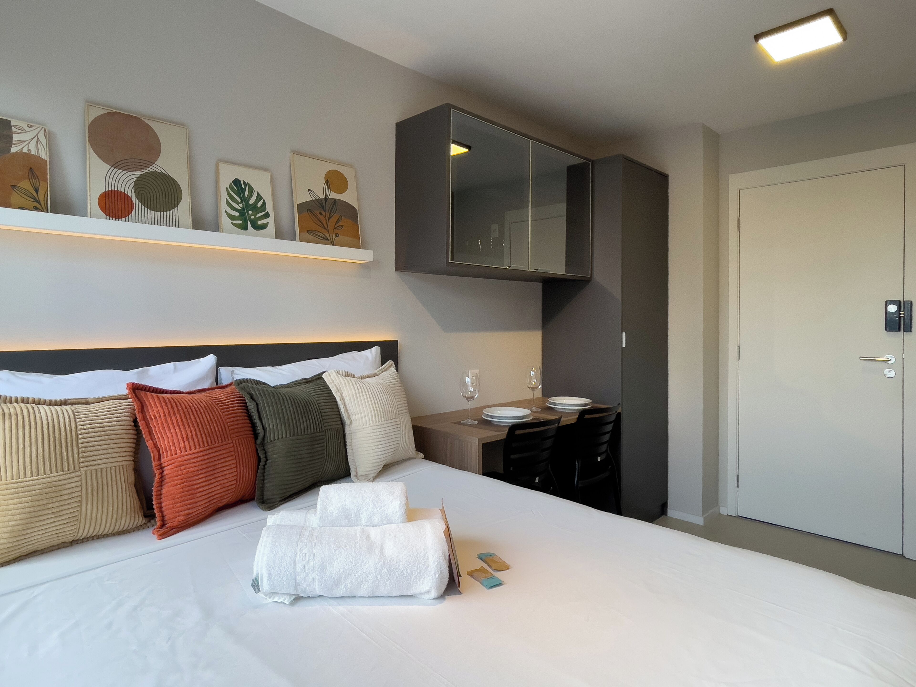 A hotel room with a large bed, a desk, and a wardrobe.