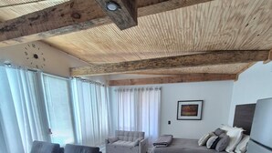 Een moderne leefruimte met een houten plafond, een eettafel, een bank en een bed.