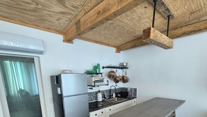 Een keuken met een houten plafond, een koelkast, een fornuis en een barkruk.