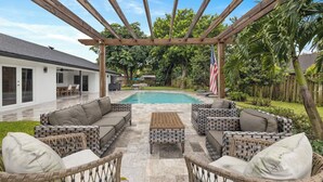 An outdoor patio with wicker furniture, a pool, and a pergola. - Luxury Wellington Pool Home! (Wellington)