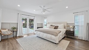 A bedroom with a large bed, a ceiling fan, and a view of the outdoors through a sliding glass door. - Luxury Wellington Pool Home! (Wellington)