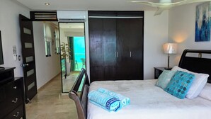 Une chambre à coucher comprenant un lit, une table de chevet, une lampe, une armoire et un ventilateur de plafond.