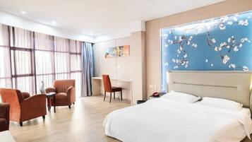 A hotel room with a bed, a desk, two chairs, and a large window with curtains.