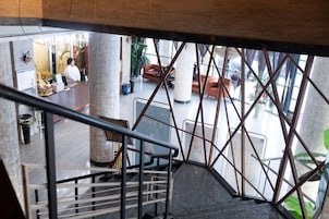 Una escalera con barandales de metal que lleva a un área de recepción con asientos y un mostrador.
