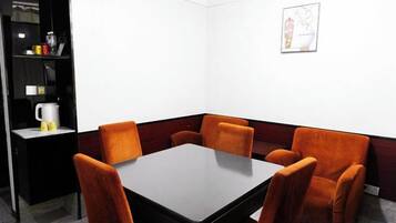 A conference room with a rectangular table and six orange chairs.