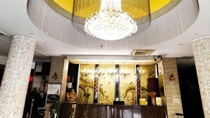 A lobby with a large chandelier, patterned columns, and a reception desk with decorative panels.