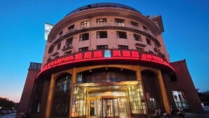 A hotel with a curved facade, large glass entrance, and illuminated signage.