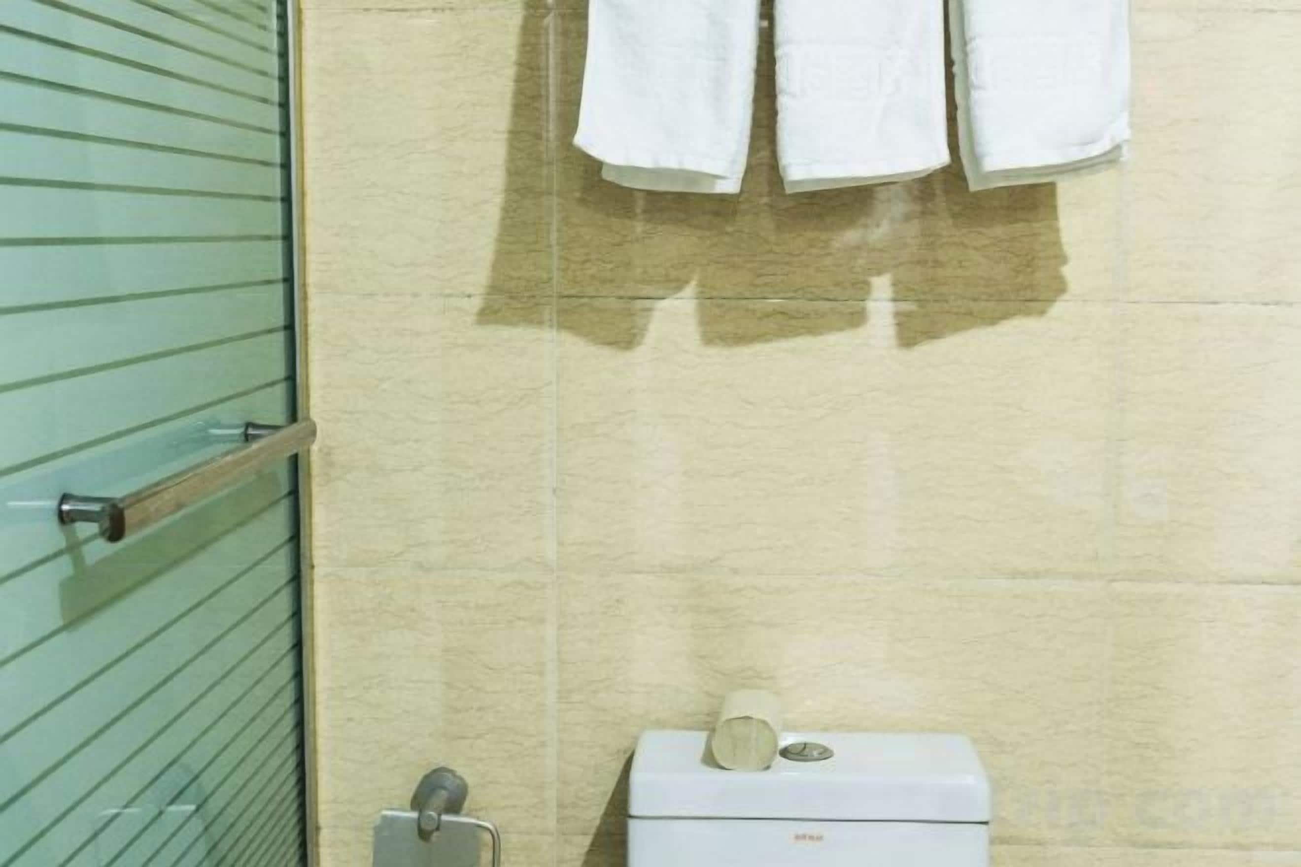 Ein Badezimmer mit Toilette, Handtuchhalter und Handtüchern sowie einer grünen Tür.