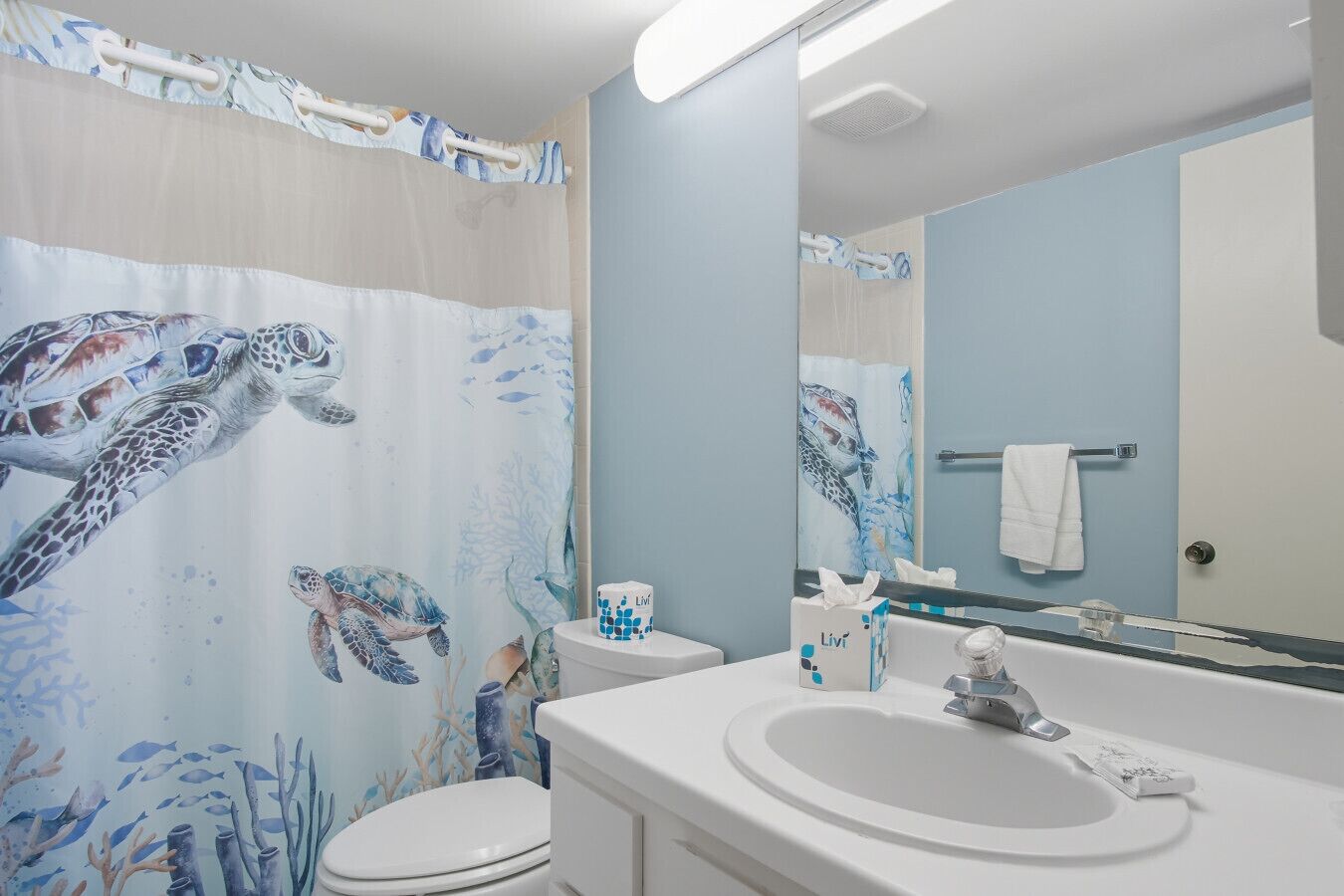 A bathroom with a sea turtle mural, a white sink, and a mirror.