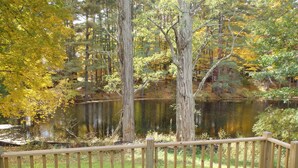 A wooden deck overlooking a pond surrounded by trees with autumn foliage. - Spacious 5-bedroom townhome with WiFi and AC in charming Bolton Landing (Bolton Landing)