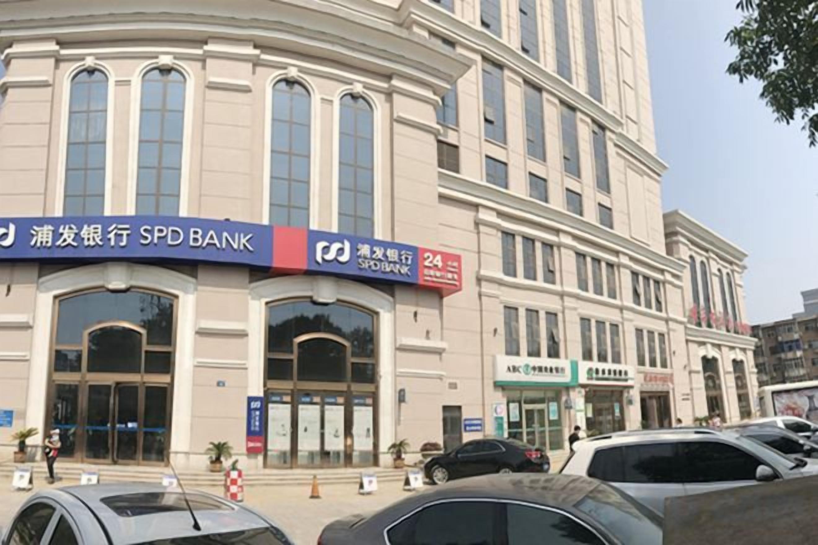A bank building with multiple entrances and a parking lot in front.