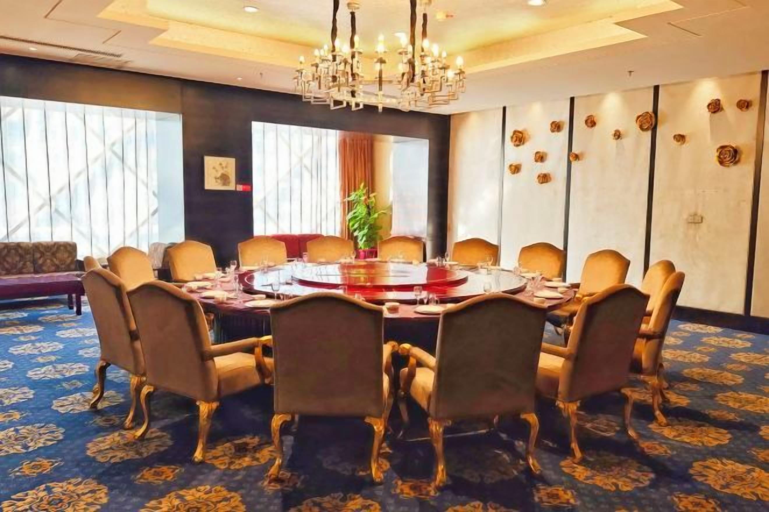 A conference room with a round table, chairs, and a chandelier.