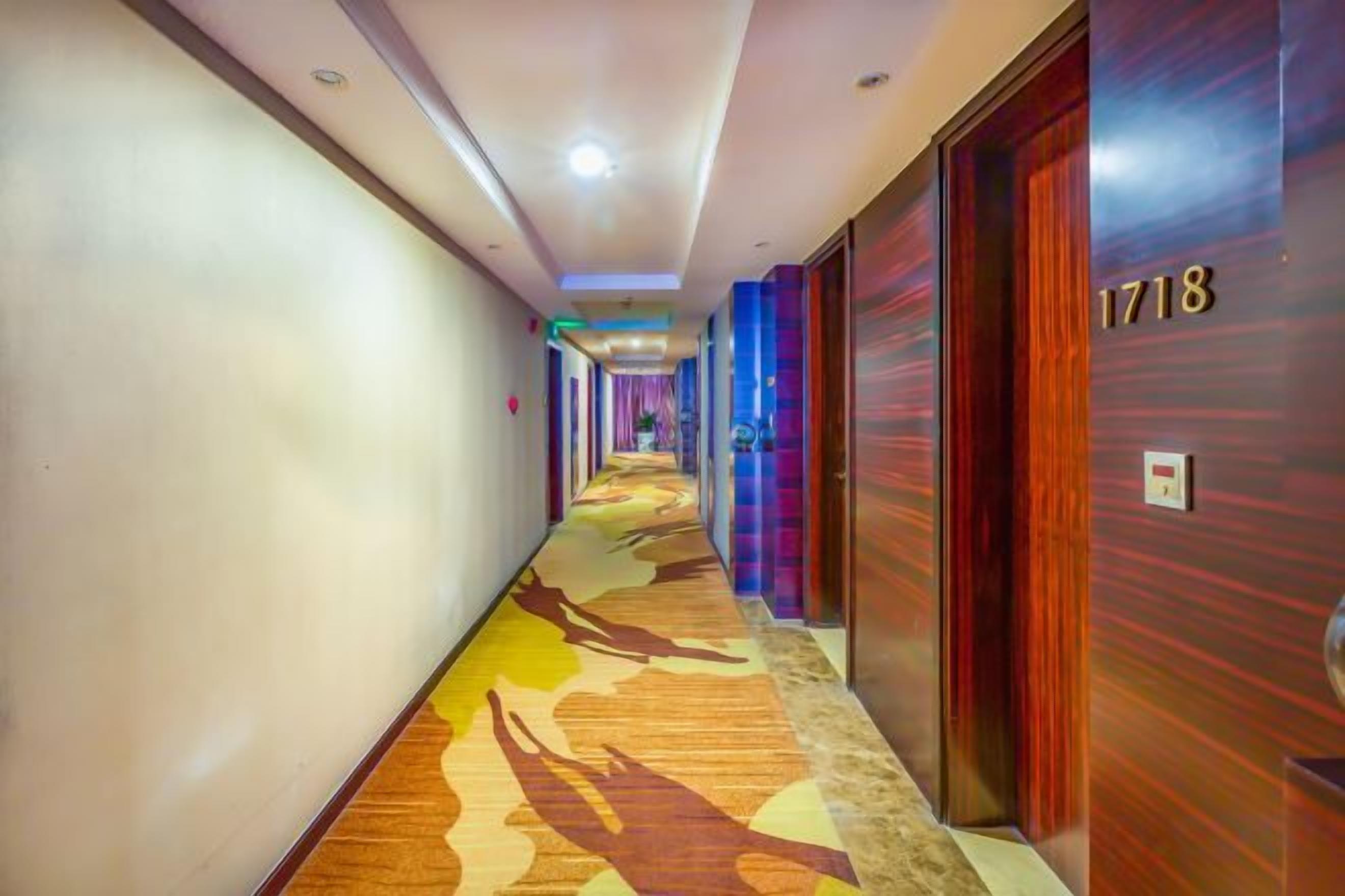 Un couloir d'hôtel avec un sol recouvert de moquette, des portes en bois et un panneau indiquant le numéro de la chambre.