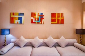A modern hotel room with a beige sofa, three abstract paintings on the wall, and two lamps. - Kunlun Hotel (Hengshui Zhongxin Street) (Hengshui)