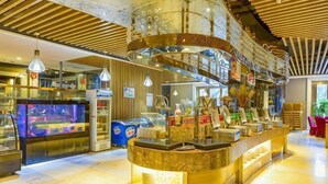 A modern bar area with a curved counter, overhead lighting, and a visible aquarium. - Kunlun Hotel (Hengshui Zhongxin Street) (Hengshui)