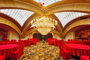 A banquet hall with round tables, red chairs, and a large chandelier. - Kunlun Hotel (Hengshui Zhongxin Street) (Hengshui)