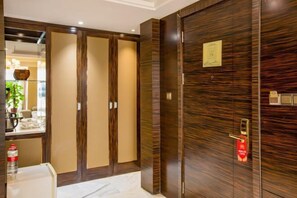 Habitación de hotel con un armario de madera grande, un espejo y una pequeña mesa con una botella.