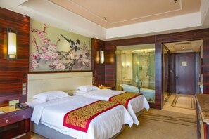 A hotel room with two beds, a large floral artwork on the wall, a bathroom with a glass shower, and a wooden floor. - Kunlun Hotel (Hengshui Zhongxin Street) (Hengshui)