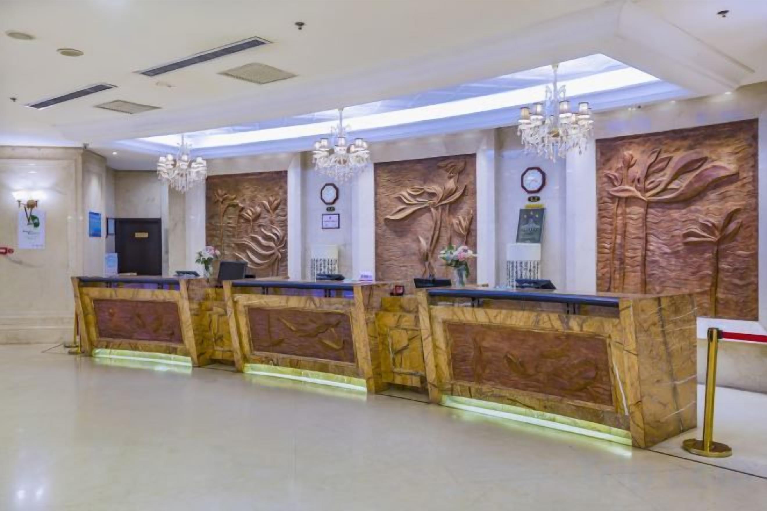 A reception area with a marble reception desk, a chandelier, and a wall-mounted clock.