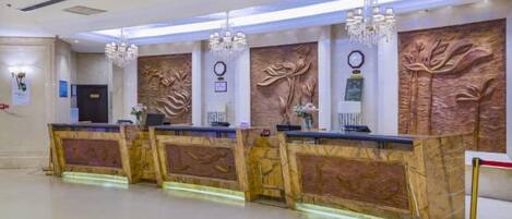 A reception area with a marble reception desk, a chandelier, and a wall-mounted clock.