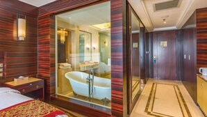 A modern hotel room with a large bed, a glass-enclosed bathroom with a bathtub, and a separate walk-in closet. - Kunlun Hotel (Hengshui Zhongxin Street) (Hengshui)
