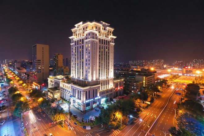 A high-rise hotel with multiple floors, surrounded by a busy urban street at night.