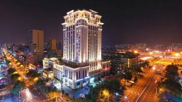 A high-rise hotel with multiple floors, surrounded by a busy urban street at night.