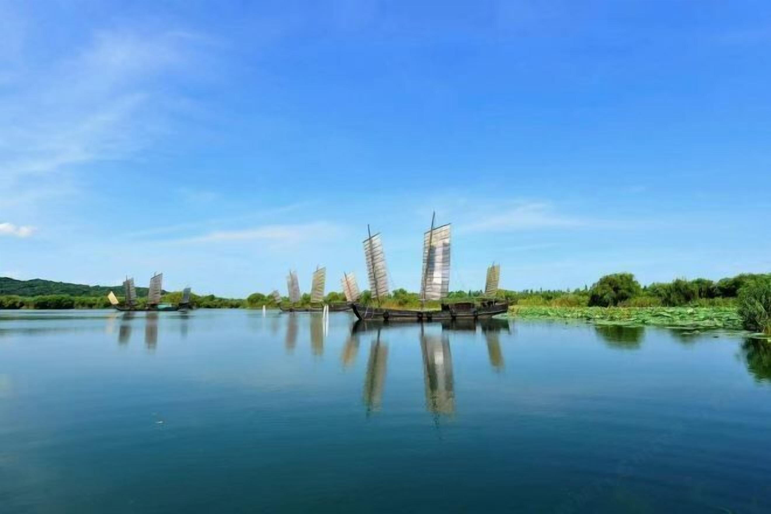 A calm river with several sailboats anchored.