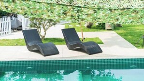 Una piscina con dos sillas de descanso y una cerca blanca de piquetes al fondo.