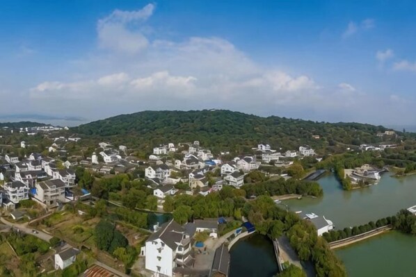 Vista aérea de un pueblo con casas, un río y una colina al fondo.