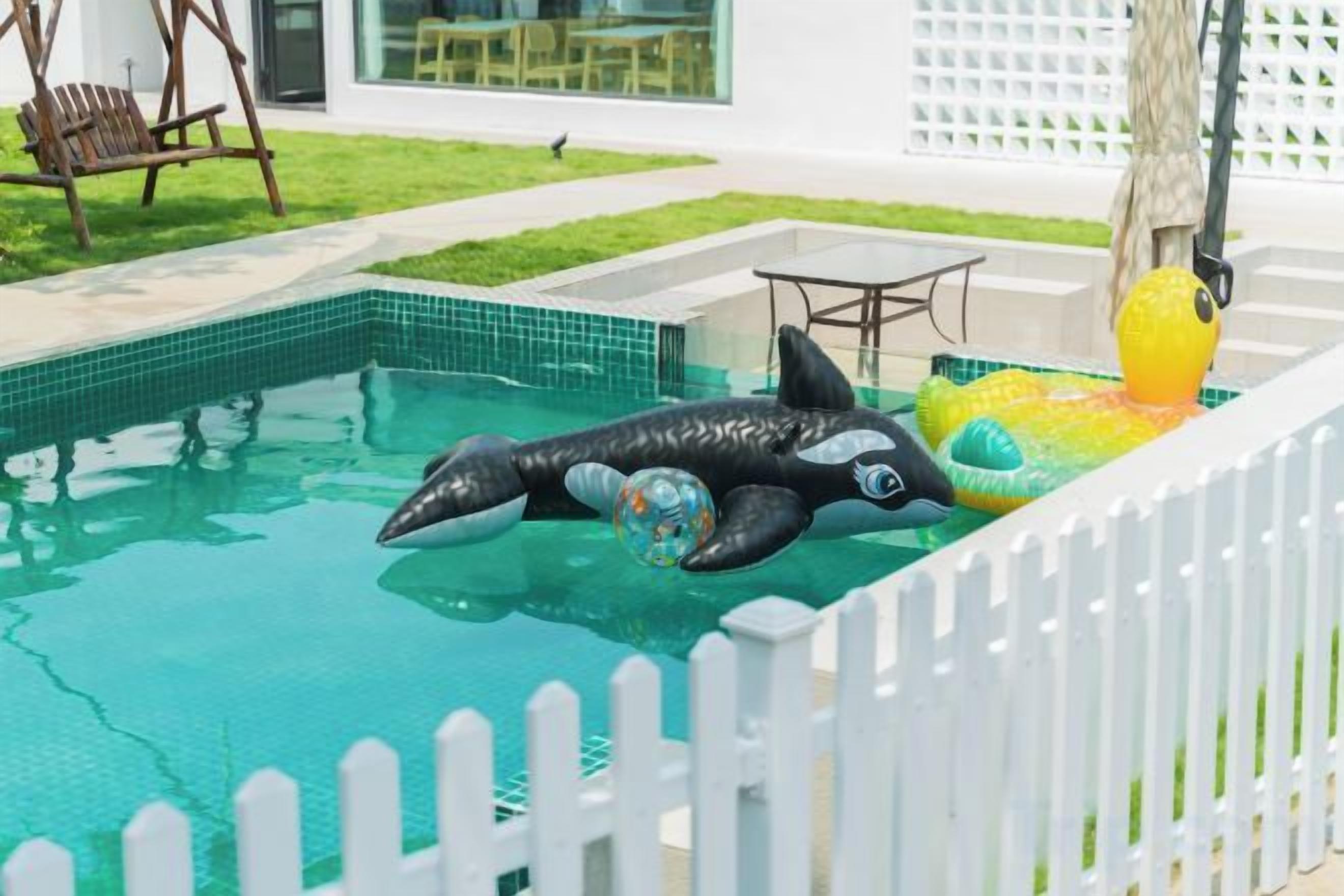 Une piscine avec un dispositif flottant en forme de dauphin et un objet gonflable jaune.