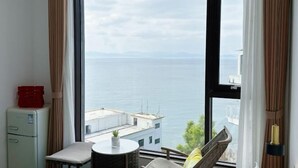 Une pièce dotée d’une grande fenêtre donnant sur la mer et les montagnes lointaines.
