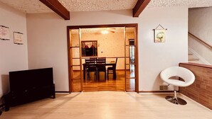 A spacious room with a wooden floor, a dining area with a table and chairs, and a white chair.