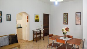 A dining area with a table and chairs, a vase with flowers, and a wall with framed pictures. - Casa Isabella (Nuoro)