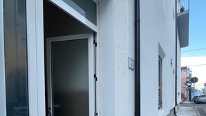 A residential building with a sliding glass door, a small outdoor step, and a visible number '8' on the wall. - Casa Isabella (Nuoro)