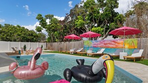 A swimming pool with inflatable toys, lounge chairs, and umbrellas.