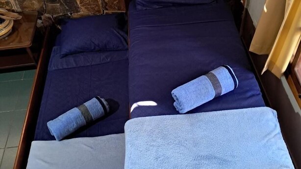 Ein Einzelbett mit Holzrahmen, zwei Kissen und zwei Handtücher.