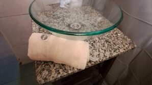 Ein Badezimmer mit einem Waschbecken aus Glas, einem Handtuch und einer Duschvorhang.