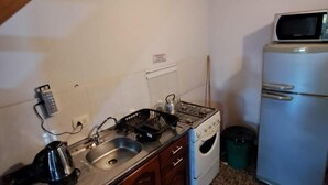 Eine kompakte Küche mit Gaskochfeld, Spüle und Mikrowelle auf einem kleinen Kühlschrank.