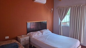 Ein Schlafzimmer mit Bett, Nachttisch und einer Klimaanlage an der Wand.