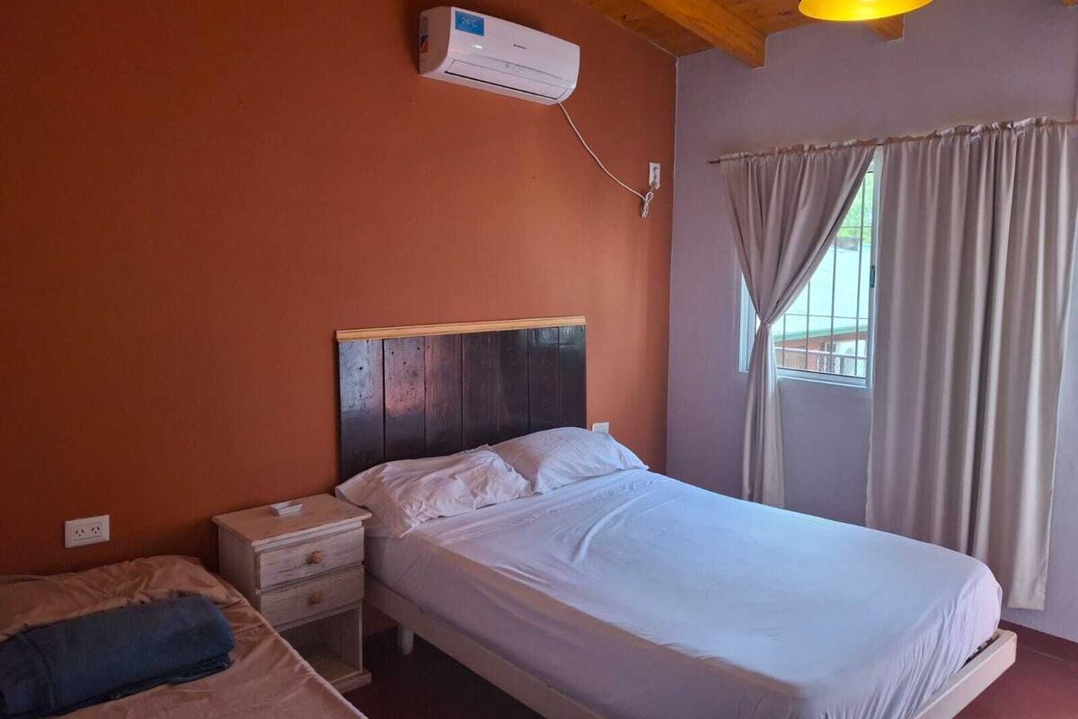 Ein Schlafzimmer mit Bett, Nachttisch und einer Klimaanlage an der Wand.