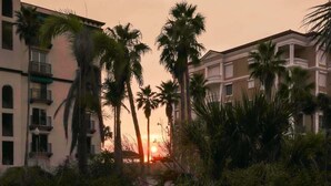 Tramonto con palme di fronte a un edificio con balconi.