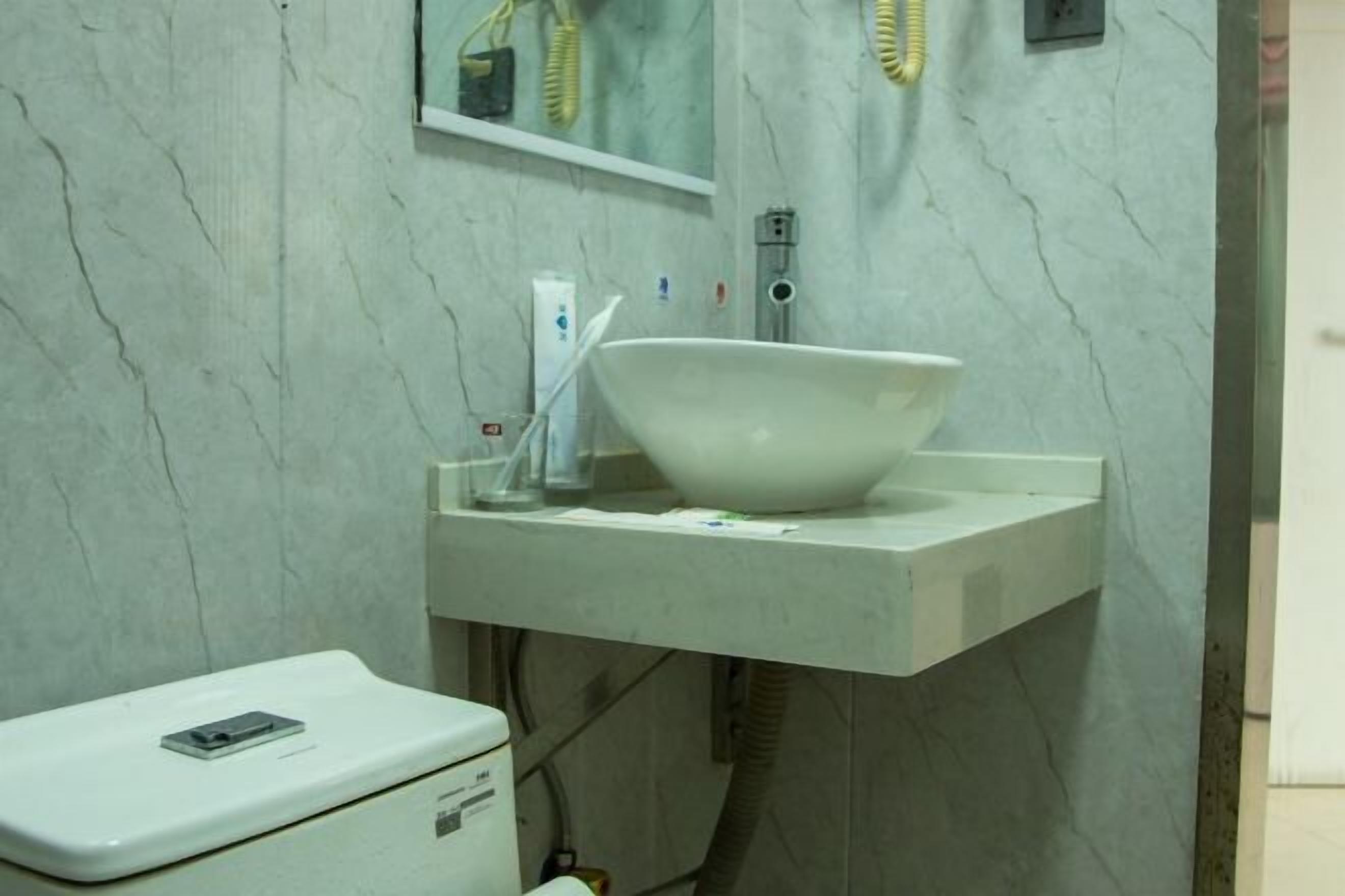 A bathroom with a white sink, a mirror, and a toilet.