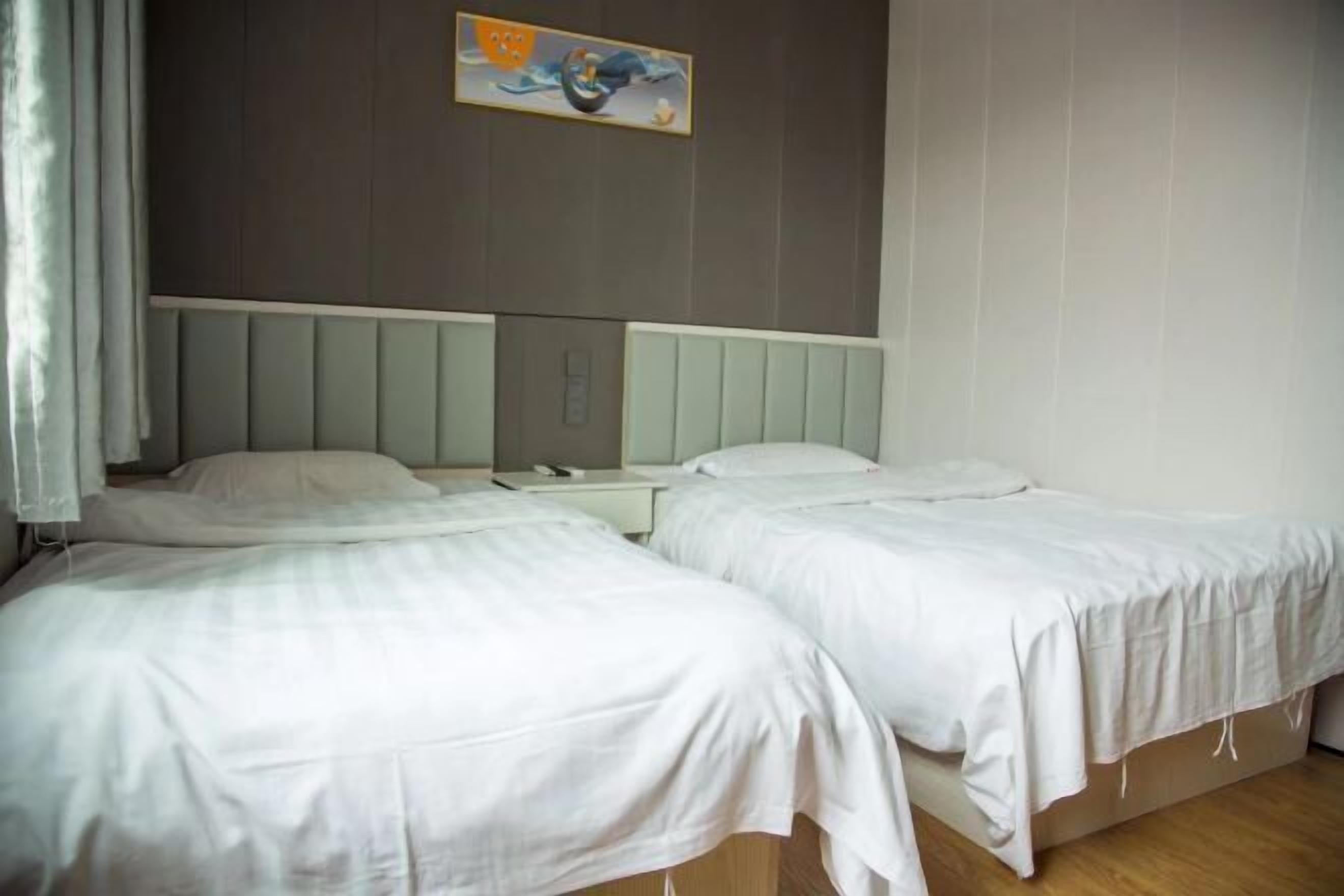 Ein Hotelzimmer mit zwei Einzelbetten, einem Nachttisch und einem Wandbild.