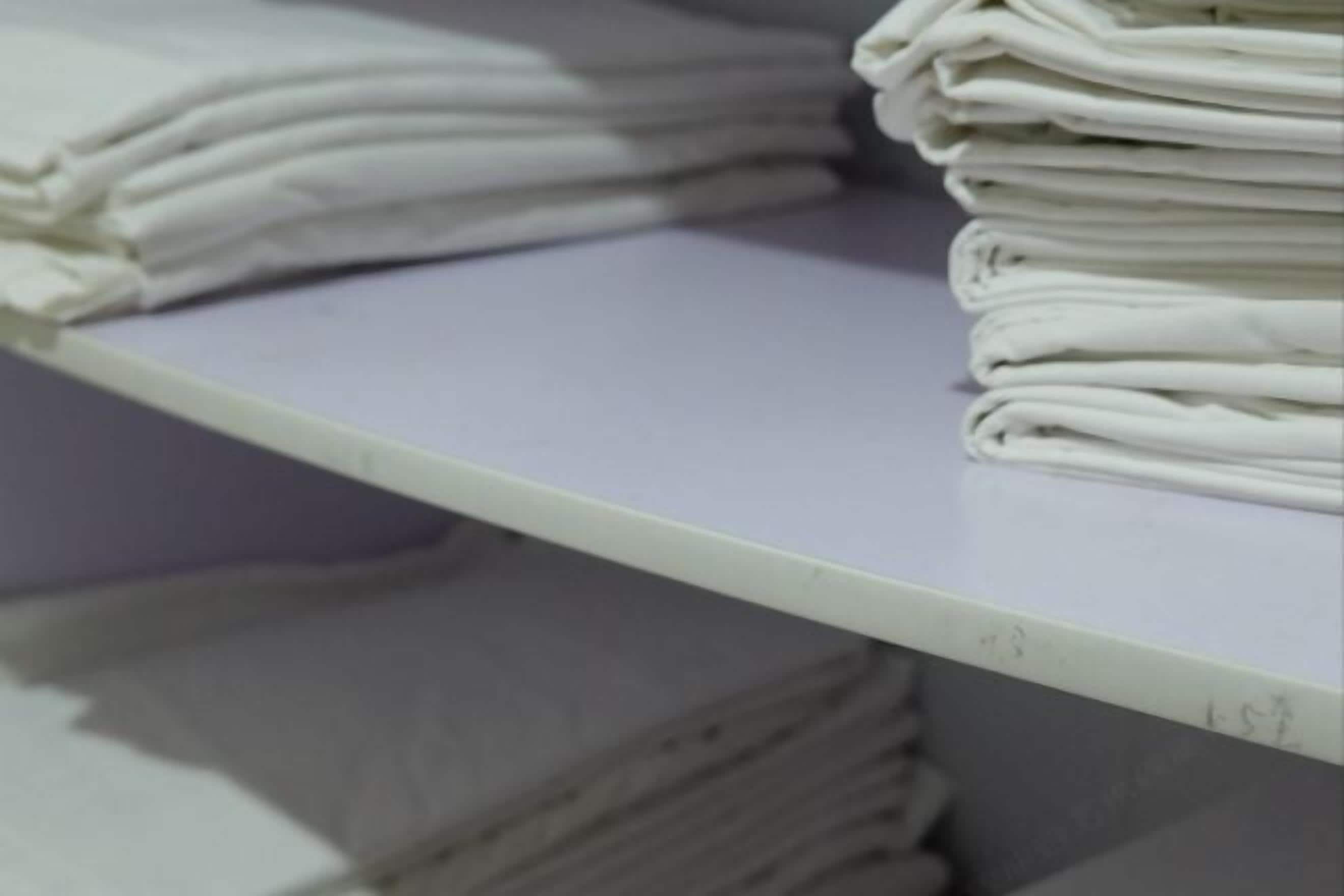 A stack of folded white towels on a shelf.