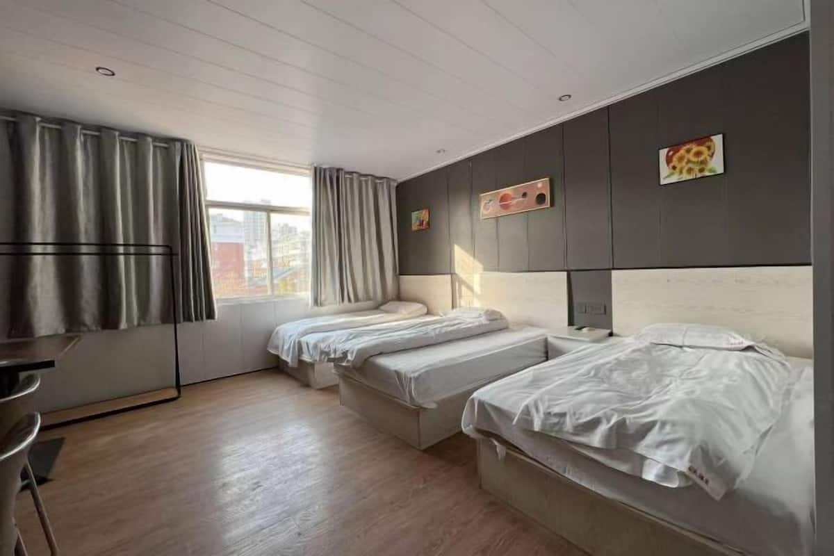 A hotel room with two beds, a desk, and a window with curtains.