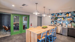 A modern kitchen with a wooden island, blue chairs, and a herringbone-patterned backsplash. - Homey Modern 3BR Retreat w/Resort Pool (Austin)